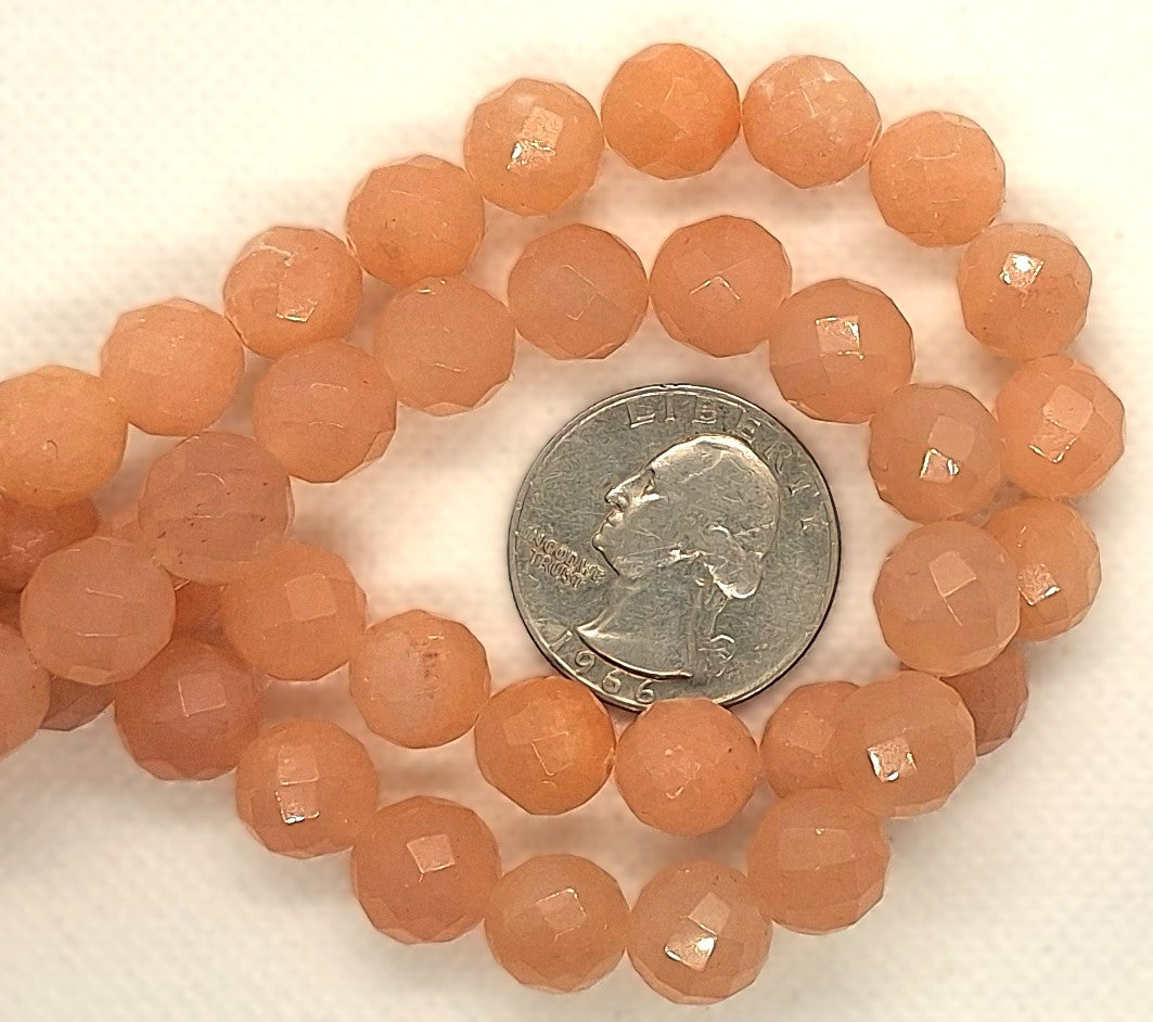 Strand of peach-colored beads with a quarter for size comparison on a white background