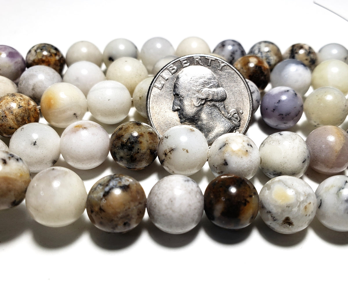 A strand of white opal round gemstone beads with a U.S. quarter for size comparison.
