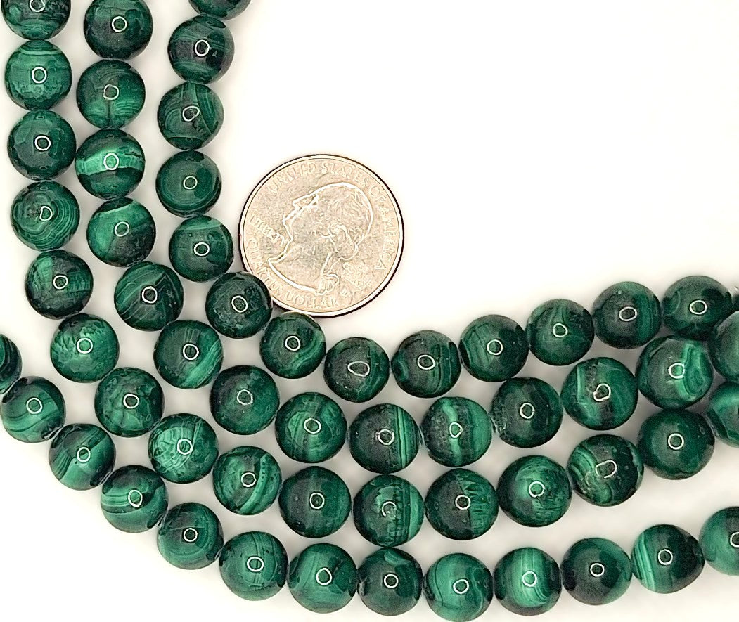 Malachite beads with dark green and light green stripes with a coin for size comparison on a white background
