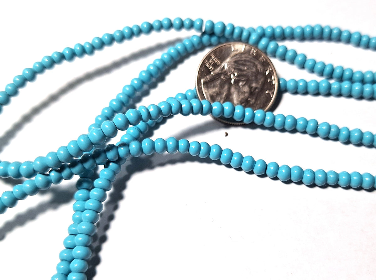 Imitation turquoise beads with a quarter for scale on a white background